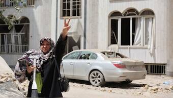 A woman shows the victory sign outside a house, following an Israeli strike on a building on Monday, after the ceasefire between Israel and Iran, in Tehran, on June 26. Reuters