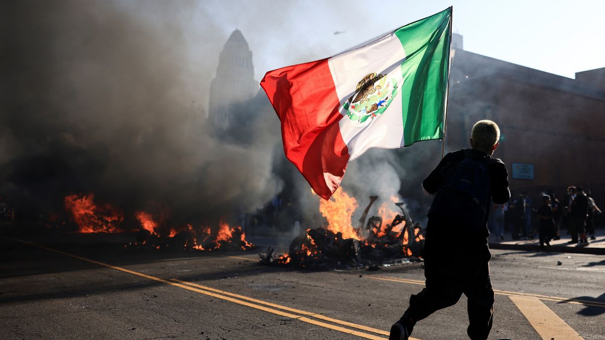 A man skates holding a Mexican flag as smoke and flames rise from burning vehicles during a protest against federal immigration sweeps, near Los Angeles City Hall in downtown Los Angeles, California, US, June 8, 2025. File Image/Reuters A man skates holding a Mexican flag as smoke and flames rise from burning vehicles during a protest against federal immigration sweeps, near Los Angeles City Hall in downtown Los Angeles, California, US, June 8, 2025. File Image/Reuters