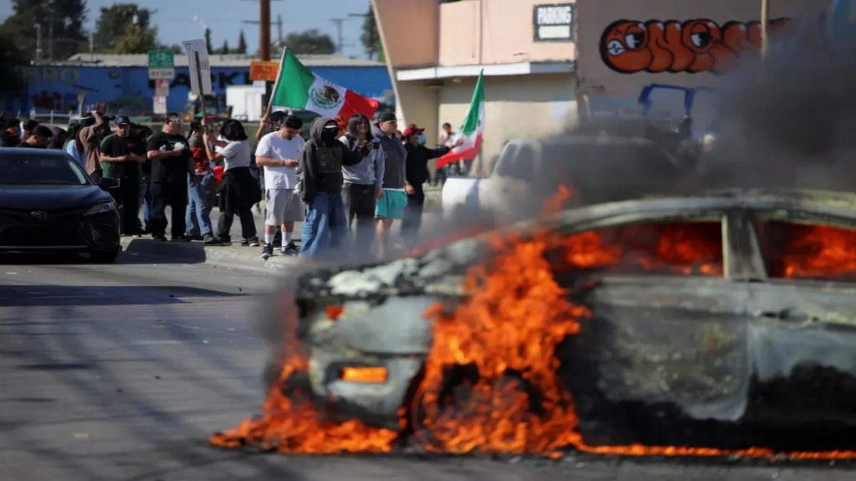 Protesters in Paramount, California, near a burning car as feds clash with rioters. Reuters Protesters in Paramount, California, near a burning car as feds clash with rioters. Reuters