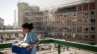A nurse carries medical supplies past a building with smoke billowing out at Soroka Hospital following an Iranian missile attack in Beersheba in southern Israel on June 19, 2025. AFP