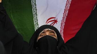 An Iranian woman holds up her country's flag in an anti-US and anti-Israeli rally at Enqelab-e-Eslami (Islamic Revolution) square in downtown Tehran. AP