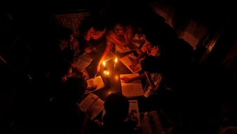 A teacher (C, top) conducts a lesson for students in the light of kerosene lamps and a candle during a power-cut inside a house in Kolkata, July 31, 2012. File Image/Reuters