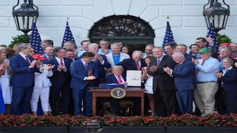 Donald Trump signs his signature bill of tax breaks and spending cuts at the White House on Friday in Washington, surrounded by members of Congress. AP