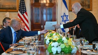 Israeli Prime Minister Benjamin Netanyahu (R) hands over a letter to US President Donald Trump as they meets at the Blue Room of the White House in Washington, DC. AFP