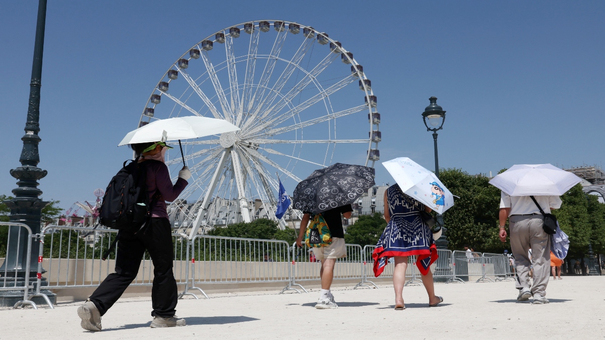 Tourists, holding an umbrella to protect themselves from the sun, walk past a Ferris wheel in the Tuileries Garden on a sunny and warm summer day in Paris as an early summer heatwave hits France, on July 2, 2025. Reuters Tourists, holding an umbrella to protect themselves from the sun, walk past a Ferris wheel in the Tuileries Garden on a sunny and warm summer day in Paris as an early summer heatwave hits France, on July 2, 2025. Reuters