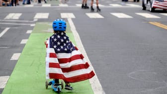 (File) Two-and-a-half-year-old Zacky Kaplan rides his scooter while draped in the American flag as he makes his way along the parade route during the Santa Monica Fourth of July Parade on July 4, 2019 in Santa Monica, California. AP