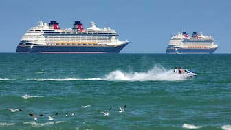 FILE - Jet skiers pass the Disney Cruise Line ships "Fantasy," left, and "Dream" on the horizon as they sit stationary off of Cocoa Beach, Fla., in this view from Lori Wilson Park, March 24, 2021. AP