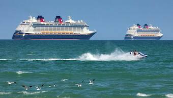 FILE - Jet skiers pass the Disney Cruise Line ships "Fantasy," left, and "Dream" on the horizon as they sit stationary off of Cocoa Beach, Fla., in this view from Lori Wilson Park, March 24, 2021. AP