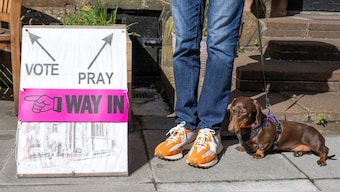 A person and a dog wait outside St James' Church polling station during the general election in Edinburgh, Scotland, Britain, July 4, 2024. File Photo/Reuters