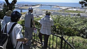 People who evacuated to Hiyoriyama mountain watch toward the sea in Ishinomaki, Miyagi prefecture, northern Japan. AP