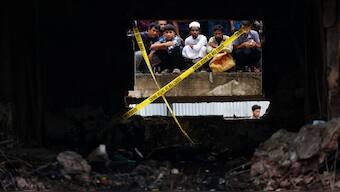 On lookers watch the site through a damaged window, after an air force training aircraft crashed into a building belong to Milestone School and College campus, in Dhaka, Bangladesh, July 22, 2025. Reuters