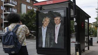 Commuters walk past a bus stop near Nine Elms Station as activists put up a poster showing President Donald Trump and Jeffrey Epstein near the US Embassy in London. AP