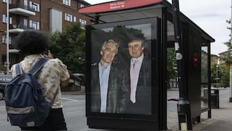 Commuters walk past a bus stop near Nine Elms Station as activists put up a poster showing President Donald Trump and Jeffrey Epstein near the US Embassy in London. AP