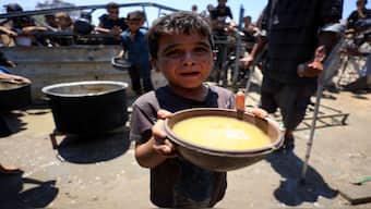 A Palestinian child holds a bowl with food received from a charity kitchen, amid a hunger crisis, in Gaza City. Reuters