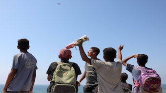 Children and youths gather as a C-130 Hercules military transport aircraft flies over during an aiddrop on the northern Gaza Strip on Sunday, July 27. Two Jordanian and one Emirati plane on dropped 25 tonnes of humanitarian aid over the Gaza Strip, Jordanian state television reported on July 27. AFP