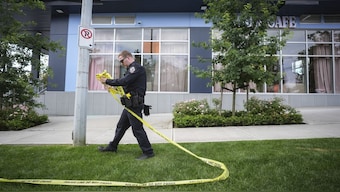 A police officer takes down crime scene tape outside the Kapil Sharma-owned cafe that was shot at multiple times, in Surrey, British Columbia, Thursday, July 10. Surrey Police investigate shots that were fired at Kap's Cafe. The Canadian Press via AP