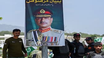 Security personnel stand beside a poster of Pakistani Army Chief General Syed Asim Munir in Islamabad. Rumours are swirling that the Pakistani army chief is preparing to oust President Asif Ali Zardari. File image/AFP