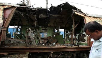 A forensic officer at the site of a damaged railway train compartment hit by the serial bomb blast in Mumbai in July 12, 2006. Seven bombs went off in the country's financial hub vital commuter rail network killing hundreds. Now, 19 years later, the 12 accused have been acquitted. File image/Reuters