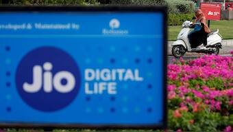 A woman rides her scooter past advertisements of Reliance Industries' Jio telecoms unit, in Ahmedabad. Reuters