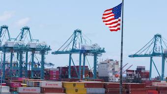 An American flag flutters over a ship and shipping containers at the Port of Los Angeles, in San Pedro California, US. File image/ Reuters