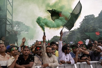 People hold Bangladesh's national flag as they celebrate during a government-organised event in Dhaka on August 5, 2025. (Photo: AFP)