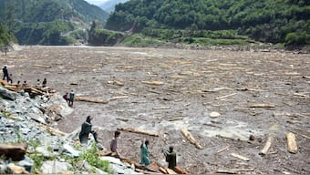 Locals collect woods from Noseri Dam near Muzaffarabad, the capital of Pakistan-administered Kashmir, on August 16, 2025, a day after flash floods. AFP