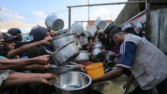 Palestinian men and boys hold out their empty pots in front of a charity kitchen in Khan Yunis in the southern Gaza Strip on August 21, 2025. (Photo: AFP)