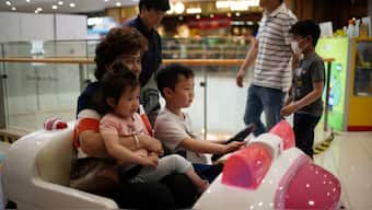 A person holds a girl as a boy drives a toy car at a shopping mall in Shanghai, China, on June 1, 2021. (Representative Photo, Credit: Aly Song/Reuters)