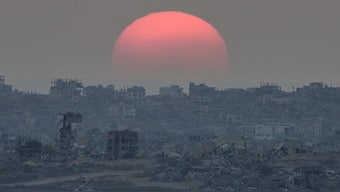 The sun sets behind buildings destroyed during Israeli ground and air operations in the Gaza Strip, as seen from southern Israel, August 26, 2025. File Image/AP