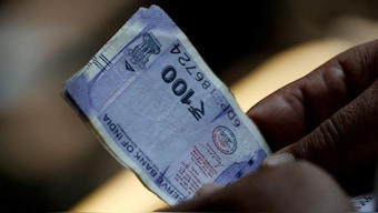 A customer holds hundred rupees Indian currency notes near a roadside currency exchange stall in New Delhi, India, May 24, 2024. File Image/Reuters