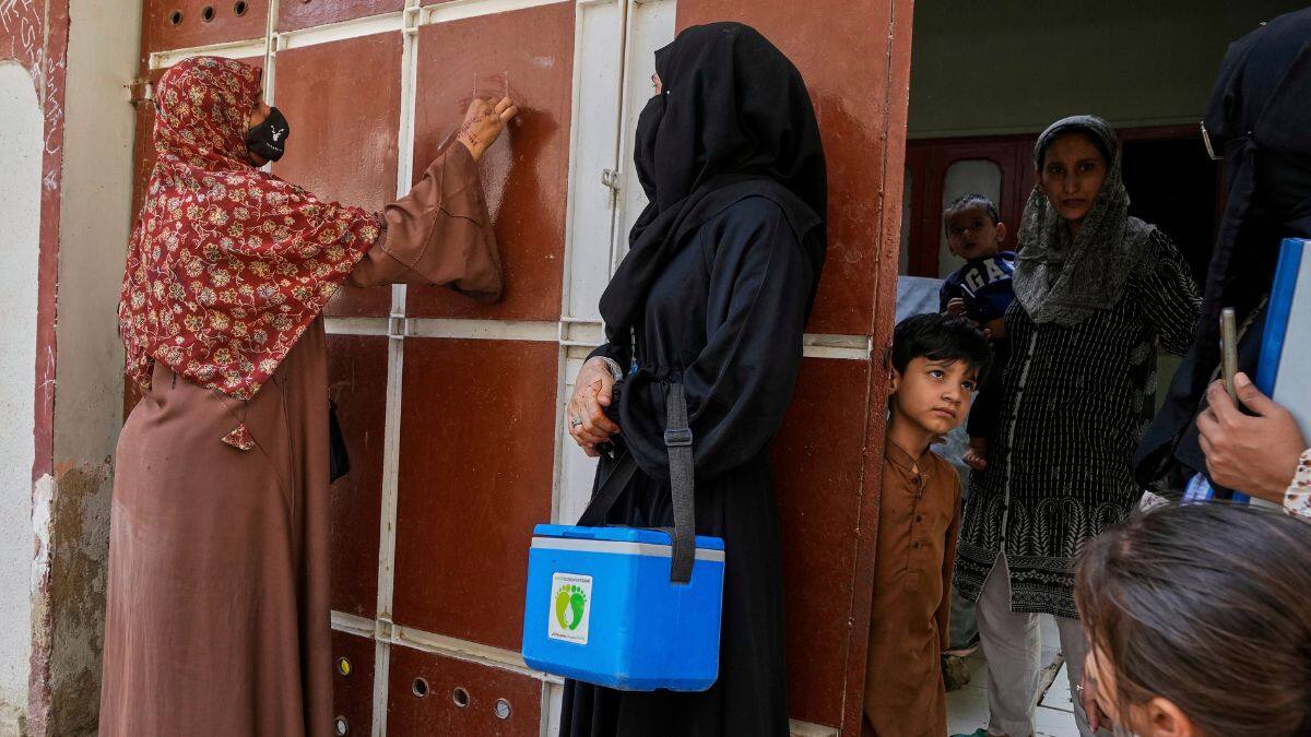 A health worker, left, marks a house after administering polio vaccines in Karachi, Pakistan, April 21, 2025. File Image/AP