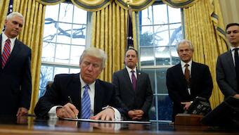 US President Donald Trump, watched by (L-R) Vice President Mike Pence, White House Chief of Staff Reince Priebus, head of the White House Trade Council Peter Navarro and senior advisor Jared Kushner, signs an executive order that places a hiring freeze on non-military federal workers in the Oval Office of the White House in Washington, January 23, 2017. File Image/Reuters