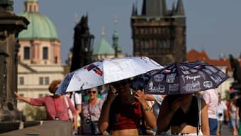 People hold umbrellas to shield themselves from the sun as they walk across the medieval Charles Bridge during a heatwave in Prague, Czech Republic, August 14, 2025. File Image/Reuters