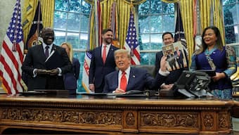 Donald Trump holds a picture of himself with Rwanda's foreign minister Olivier Nduhungirehe, at a meeting in June. Pic: Reuters
