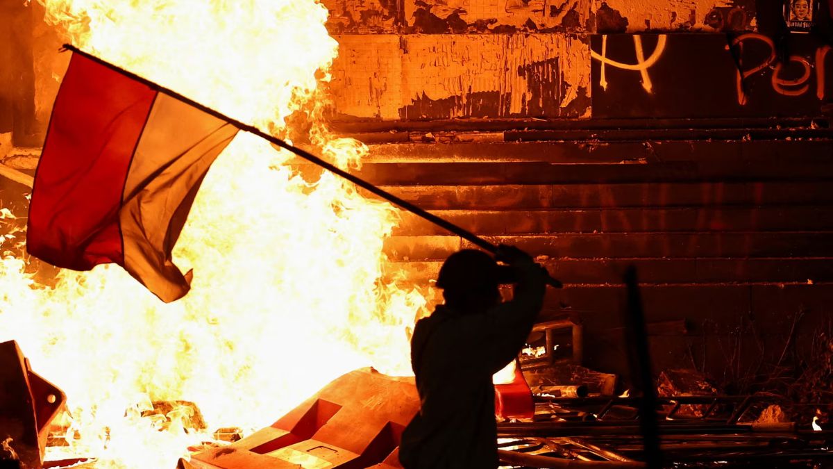 A protester carrying an Indonesian flag walks past the gate of Jakarta police headquarters which is set on fire during a protest. Image- Reuters A protester carrying an Indonesian flag walks past the gate of Jakarta police headquarters which is set on fire during a protest. Image- Reuters