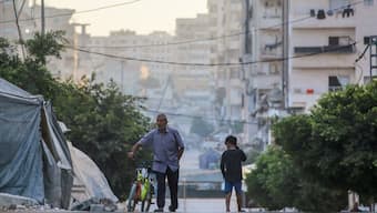 A man pushes a bicycle past a boy on a street in Gaza City on August 29, 2025, as the war between Israel and the Hamas terrorists movement continues. Image- AFP