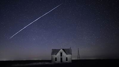 In this long exposure photo, a string of SpaceX StarLink satellites passes over an old stone house near Florence, Kansas. AP