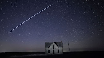 In this long exposure photo, a string of SpaceX StarLink satellites passes over an old stone house near Florence, Kansas. AP