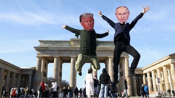 People wearing head cut-outs depicting US President Donald Trump and Russian President Vladimir Putin jump during a protest at the Brandenburg Gate in Berlin, Germany, February 20, 2025. File Image/Reuters