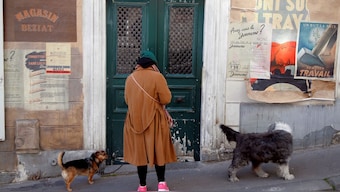 A local resident walks her dogs past War propoganda posters in the Montmarte district in Paris on March 25, 2020. File Photo/Reuters 