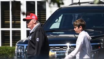 US President Donald Trump walks through the parking lot with grandson Spencer Frederick Trump (R) at Trump National golf course in Sterling, Virginia, on August 30, 2025. AFP
