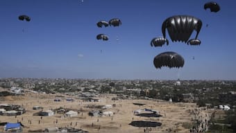Palestinians rush to collect humanitarian aid airdropped in central Gaza Strip. AP