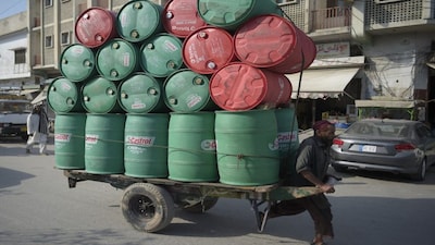 A labourer pulls his cart laden with empty oil drums in Rawalpindi. File image/AFP