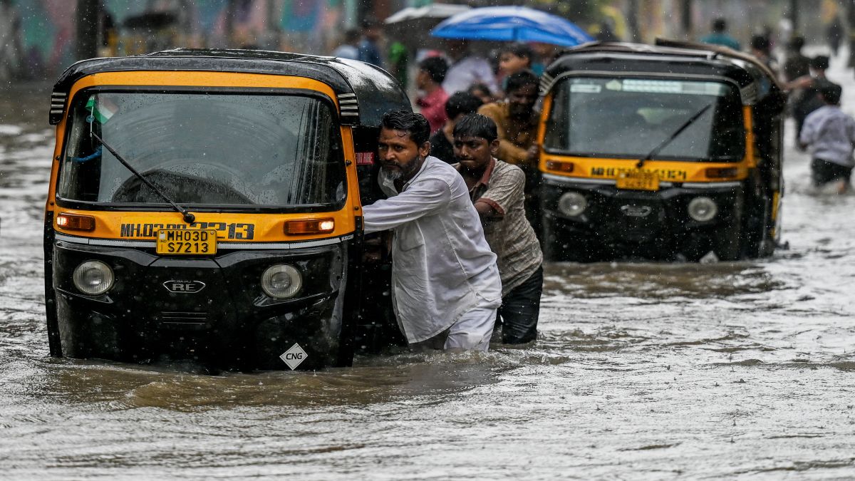Drivers push their auto-rickshaws through a flooded street during heavy rain showers in Mumbai on Monday. AFP Drivers push their auto-rickshaws through a flooded street during heavy rain showers in Mumbai on Monday. AFP