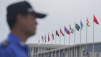 A security guard stands near the flags of Shanghai Cooperation Organisation (SCO) member states outside the venue in Tianjin, China , Saturday (August 30). PM Modi will be heading to the industrial hub, where he will hold a bilateral with Xi Jinping and attend the SCO Summit. AP