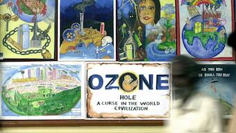 A visitor (right) walks past a display of award-winning paintings by students at a function on the occasion of International Day for the Preservation of the Ozone Layer in Bangalore, September 16, 2002. (Photo: Indranil Mukherjee/AFP)