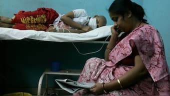 A woman reads a newspaper as her daughter, a cancer patient, rests in a hospital in the eastern Indian city of Kolkata on World Cancer Day February 4, 2009. (Photo: Parth Sanyal/Reuters)