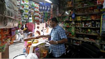 An owner of a store selling consumer goods, attends to a customer at his store in Dharavi, Mumbai, in Maharashtra, India, November 18, 2021. File Image/Reuters