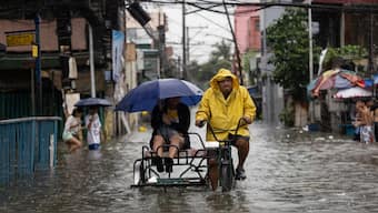 A person is transported as residents wade through a flooded road amid monsoon rains in Malabon City, Philippines, July 24, 2025. File Photo/Reuters