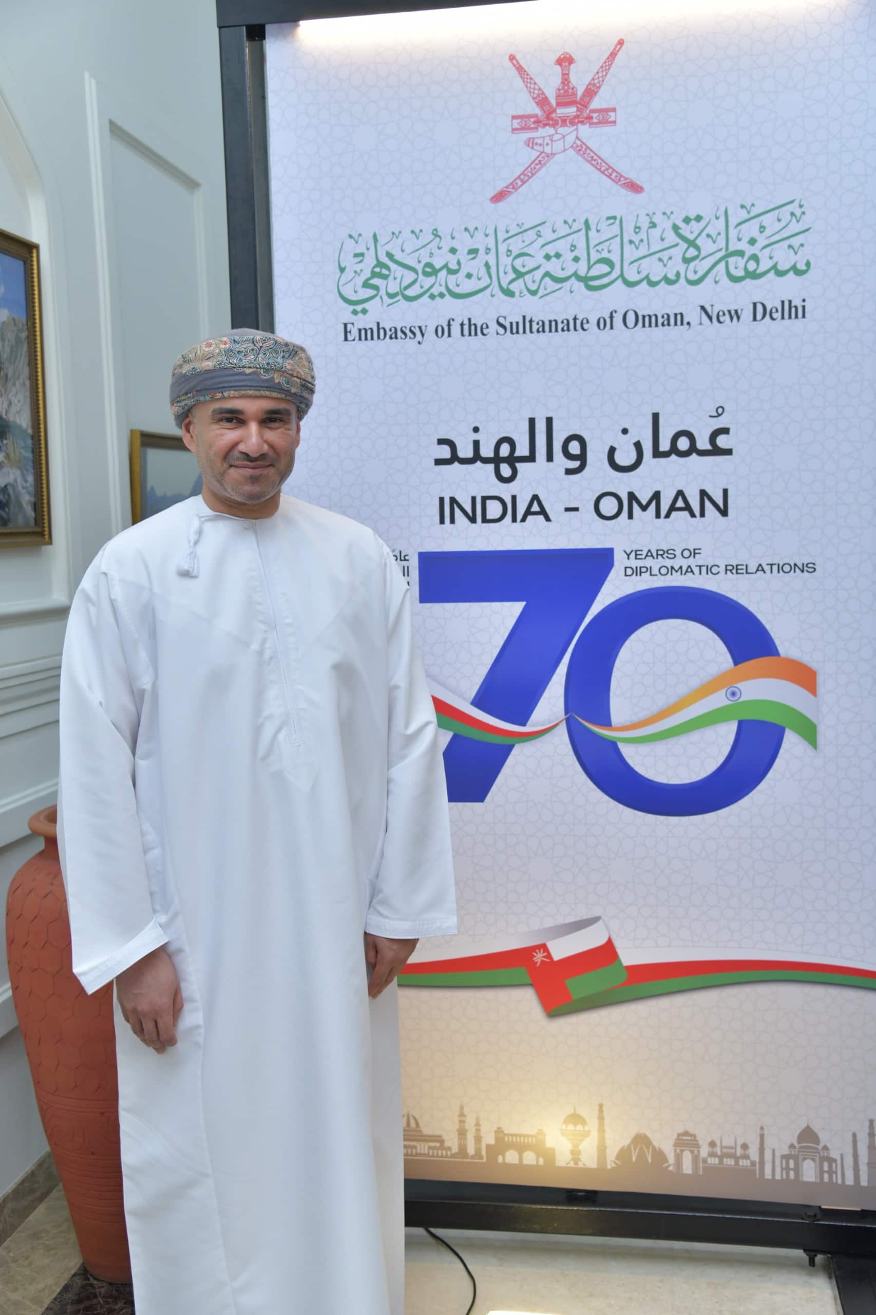 general Oman's Ambassador to India Issa Saleh Alshibani stands next to the logo designed to commemorate 70 years of diplomatic ties between India and Oman. Image Source: Embassy of The Sultanate of Oman 